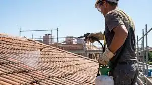 Professionnel nettoyant une toiture tuiles au nettoyeur haute pression – traitement anti-mousse avant la pluie