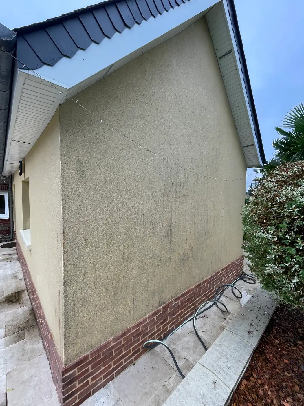 Avant nettoyage de façade à Courseulles-sur-Mer par Normandie Nettoyage — nettoyage pignon enduit projeté avec soubassement brique – algues vertes et salissures Calvados (14470)