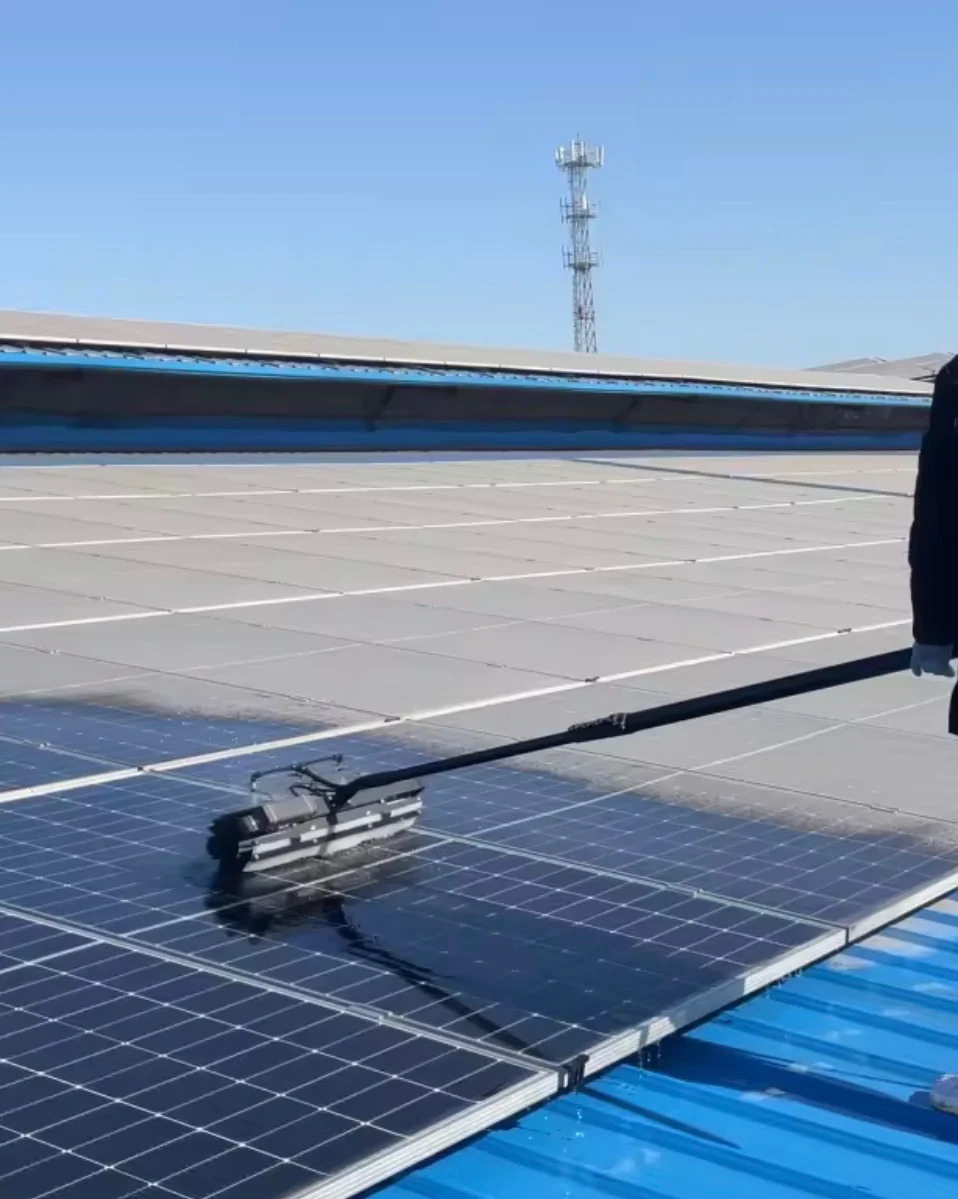 Nettoyage de panneaux solaires à la brosse rotative sur perche : contraste net entre les panneaux encrassés de poussière grise et les panneaux nettoyés retrouvant leur surface bleue
